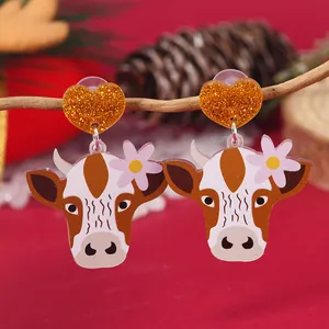 Close-up of acrylic cow earrings with glitter hearts hanging on festive branches