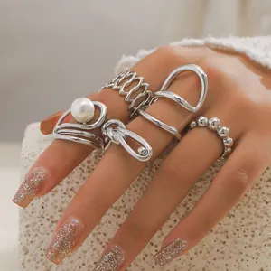 Vue détaillée d'un ensemble de 5 bagues argentées avec perles sur la main d'un mannequin
