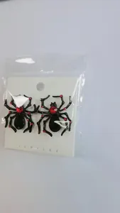 Macro detail of black spider earrings featuring red rhinestones in original packaging