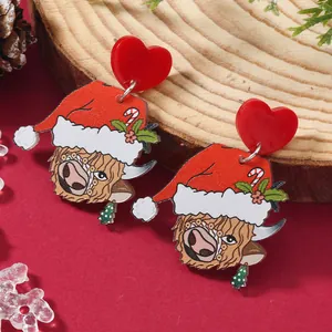 Detail of Christmas acrylic earrings featuring cute Highland cow with festive red Santa hat