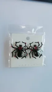 Detail of black spider stud earrings with red crystals on a white display card