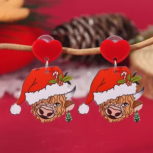 Close-up of Christmas highland cow earrings with red heart studs and festive hat
