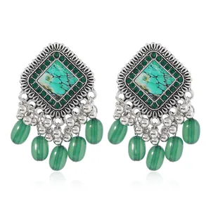 Detail of vintage bohemian earrings with turquoise stones and silver bell charms