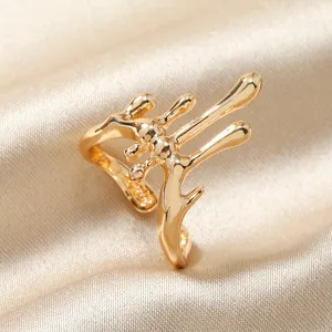 Gros plan d'une bague dorée au design métal liquide sur un tissu de soie luxe
