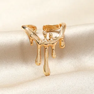 Détail macro d'une bague dorée au design liquide fondu sur fond de soie champagne