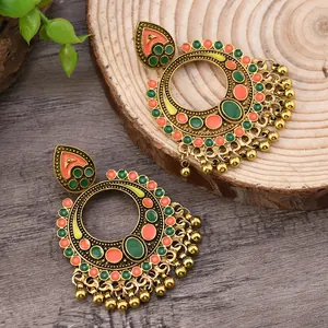 Detail of vintage bohemian alloy hoop earrings with green enamel and gold bead tassels