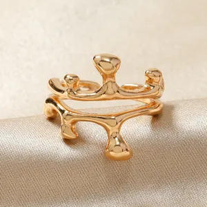 Gros plan d'une bague irrégulière dorée style lave liquide sur satin de soie champagne