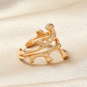 Vue détaillée d'une bague dorée irrégulière sur un fond en soie couleur champagne