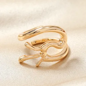 Détail macro d'une bague ouverte dorée style lave sur fond de soie champagne