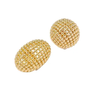 Vue détaillée de boucles d'oreilles boules dorées évidées au design de perles précis