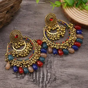 Detail of vintage bohemian oversized drop earrings with colorful beads on dark wood background