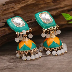 Macro shot of Bohemian Jhumka earrings with colorful enamel lotus pattern and white beads