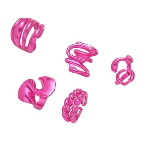 Détail de cinq bagues d'oreille Y2K rose vif avec des designs texturés et ondulés