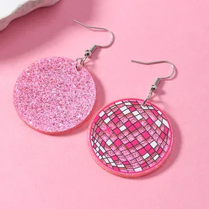 Dettaglio di orecchini tondi in acrilico rosa glitterato e motivo a palla da discoteca