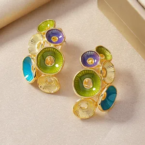 Dettaglio di orecchini colorati con nappe in smalto verde e finitura dorata
