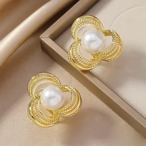 Dettaglio degli orecchini a fiore dorati con perle su elegante sfondo di raso