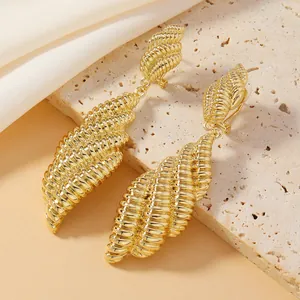 Dettaglio macro di orecchini a conchiglia placcati in oro con motivi a spirale su pietra