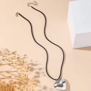 Minimalistische silberne Herz-Halskette mit schwarzer Kordel auf elegantem Hintergrund