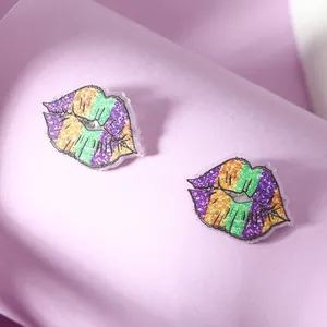 Detail of lip-shaped acrylic earrings with purple, green, and orange Mardi Gras glitter stripes