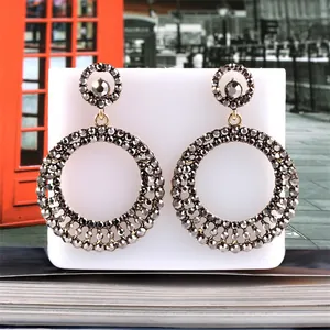 Detailed view of large double hoop earrings featuring grey rhinestones on a white display