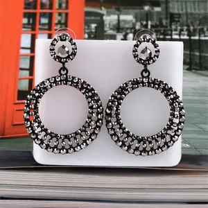 Macro detail of gunmetal fan earrings with grey rhinestones on a white display board