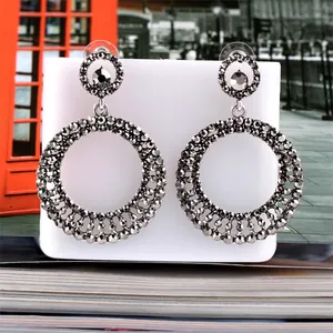 Detail view of large circular drop earrings featuring gunmetal grey pavé rhinestones