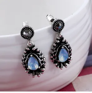 Detailed view of vintage teardrop earrings with pear-shaped opal stones on white ceramic