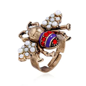 Detailed macro shot of a vintage gold bee ring with pearls and purple enamel stripes