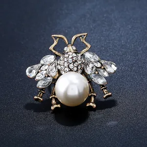 Macro shot of vintage gold bee brooch with large pearl and sparkling rhinestones