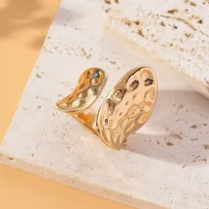 Detailed macro shot of a gold hammer-textured adjustable ring on white stone base