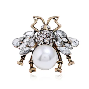 Vintage gold bee ring featuring crystal wings and a large white pearl center on white base