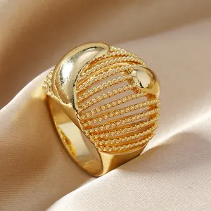 Elegant gold-tone hollow cage ring with beaded layers on champagne silk background