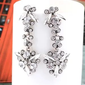 Detail of silver long fan-shaped tassel earrings with zircon stones and floral pattern