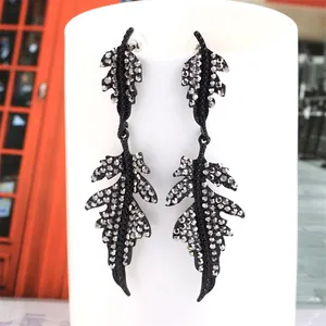 Detail of long leaf-shaped earrings featuring black finish and grey zircon stone pavé