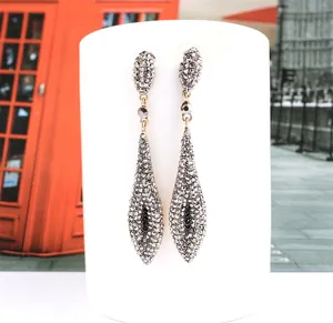 Macro shot of long teardrop tassel earrings with grey pavé crystals and gold plating
