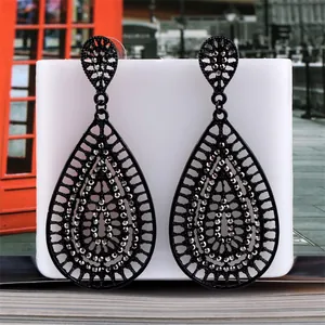 Close-up of black hollow teardrop earrings with crystals and vintage geometric patterns