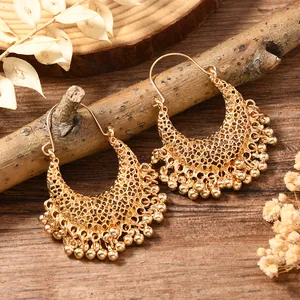 Detail of gold-plated hollow mesh earrings with metal bead tassels on a branch