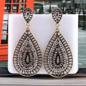 Macro view of vintage hollow teardrop earrings with crystals on a white display