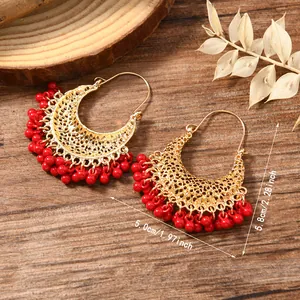 Detail of bohemian gold-plated hoop earrings with red beads and hollow carving