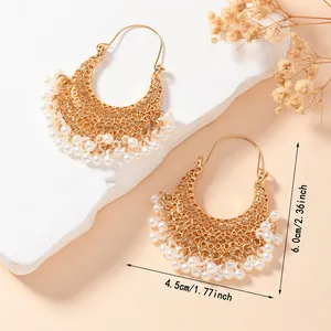 Detail view of gold-plated hollow vintage earrings with white pearl tassel fringes