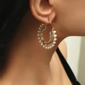 Detailed view of luxury gold hoop earring with white pearls and sparkling zircons