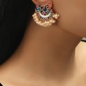 Detailed close-up of peacock enamel Jhumka earrings with pearls and gold plating