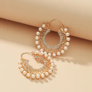 Close-up of gold plated hoop earrings with hollow metal patterns and white pearls