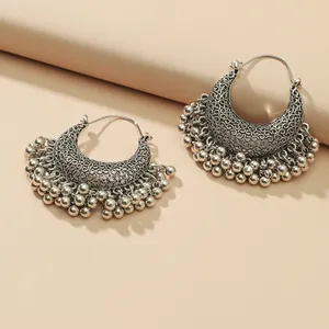 Bohemian crescent filigree drop earrings with metallic tassels on a beige background