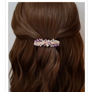 Elegant rhinestone flower hair clip with purple gems on wavy brown hair back view