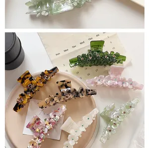 Close-up of acetic acid hair claws with 3D floral designs and sparkling rhinestone centers