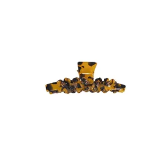 Tortoiseshell acetate hair claw clip with rhinestones and floral accents on white background