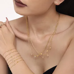 Detail of 18K gold-plated clover jewelry set with sparkling crystals and letter pendants