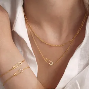 Detail of 18k gold plated safety pin layered necklace with sparkling zircon stones