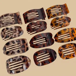 Vista piatta di 12 mollette per capelli leopardate in varie forme geometriche opache